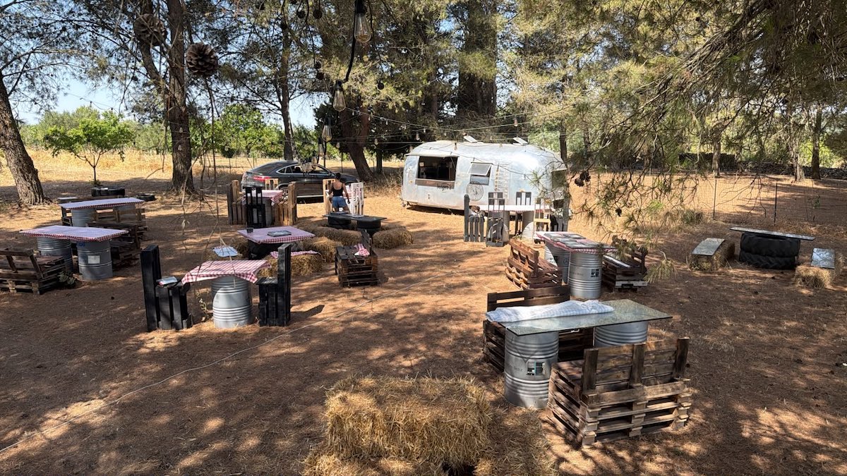 Kitchentruck Burger's Garden dans les Pouilles avec food truck Airstream et tables sous les pins